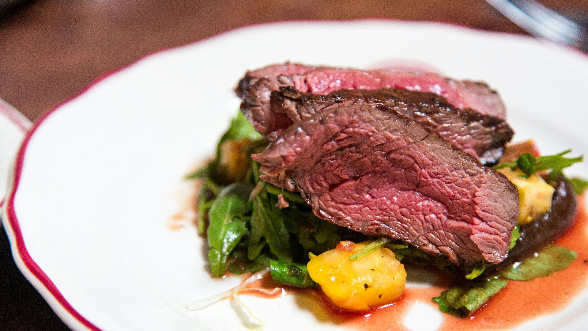 medium rare sliced steak in white ceramic plate