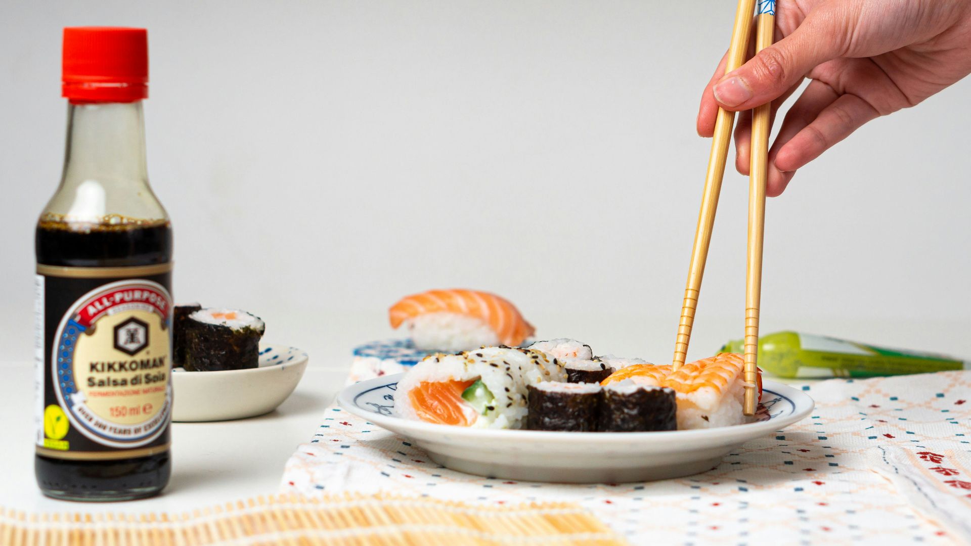 a person holding chopsticks over a plate of sushi