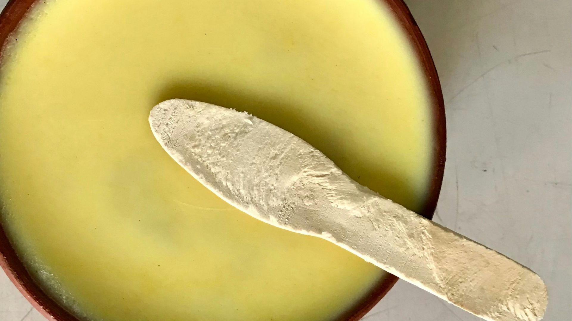 A spoon in a bowl with a liquid inside of it