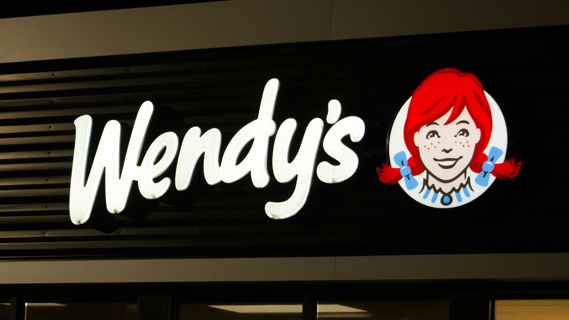 A wendy's sign is lit up at night