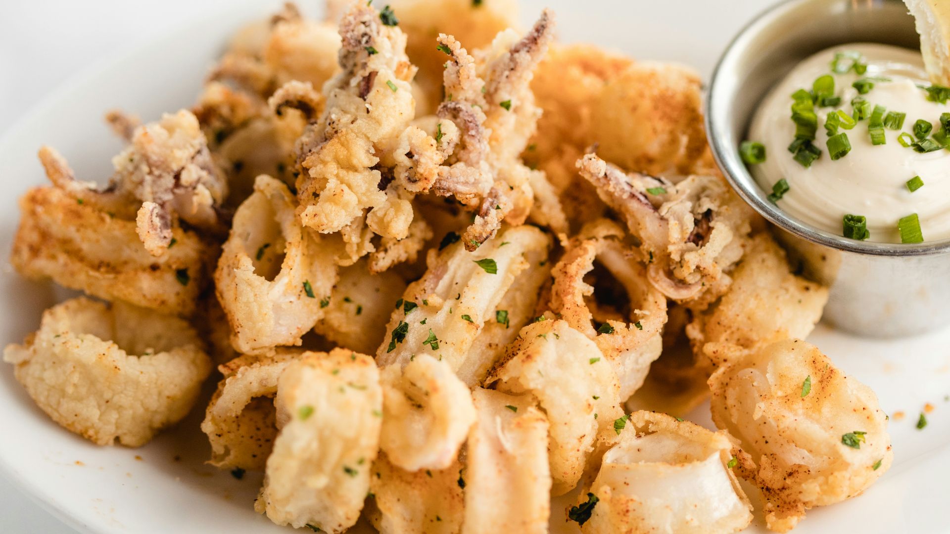 a white plate topped with fried food and a dipping sauce