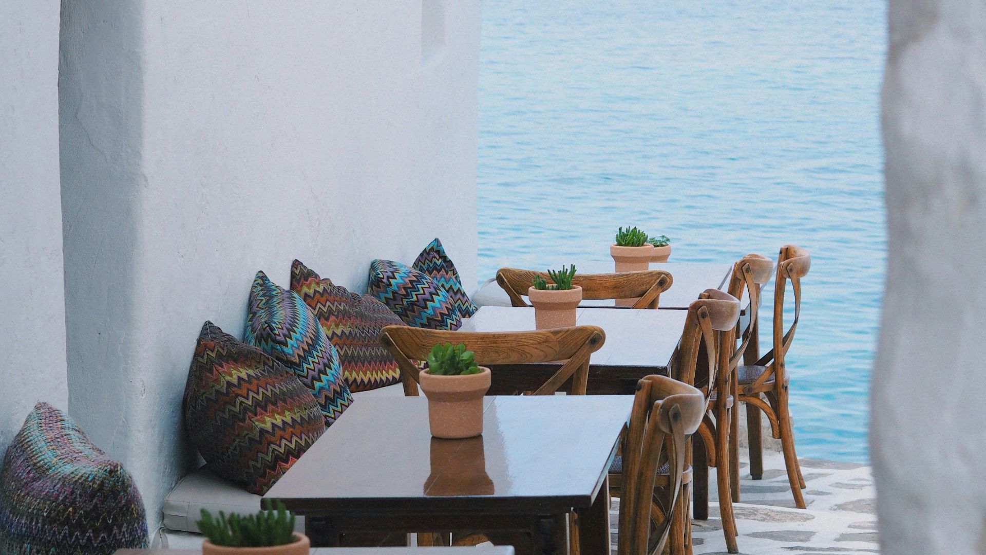 a row of wooden tables sitting next to a body of water