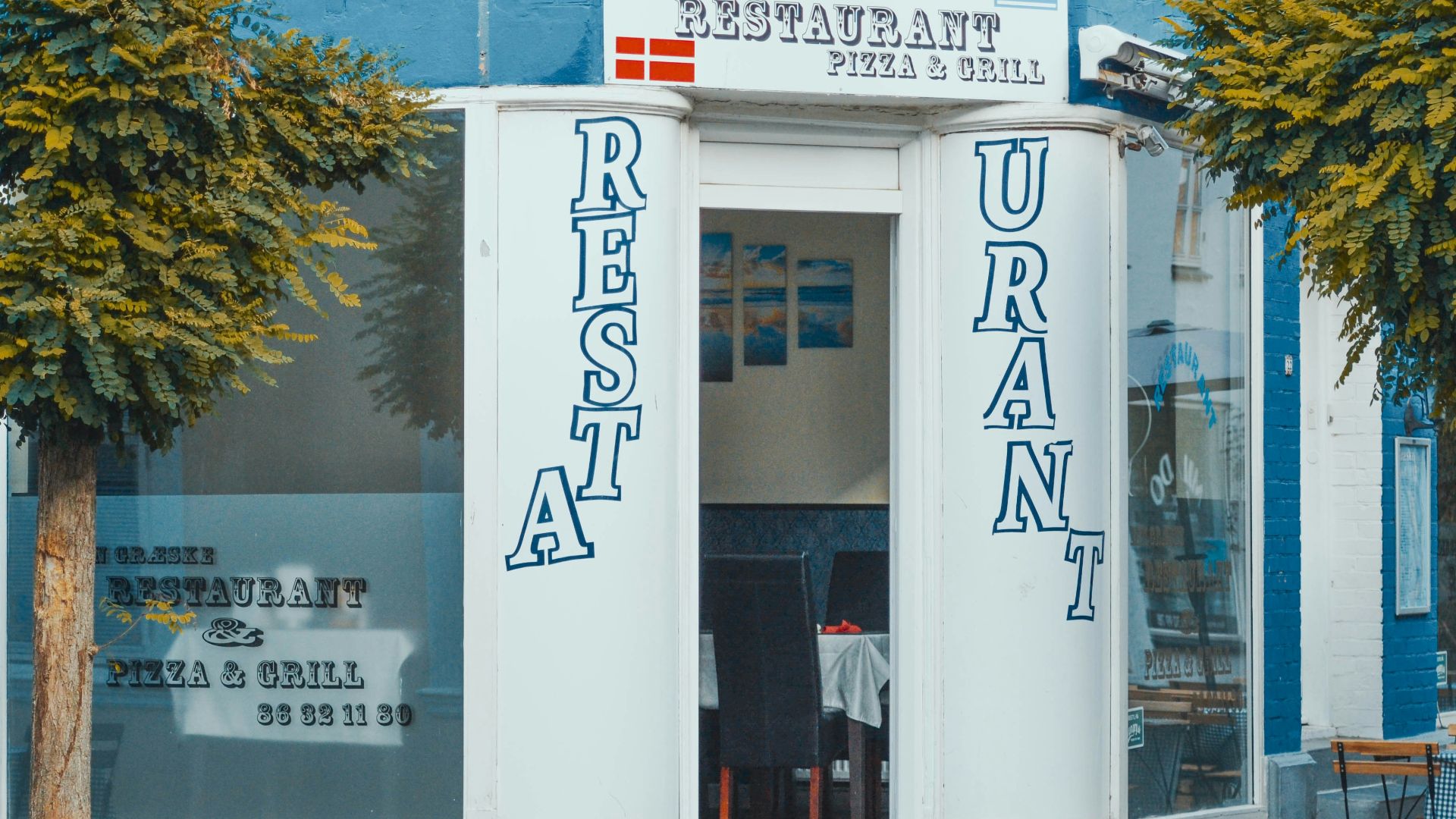 white and blue concrete building near green tree during daytime