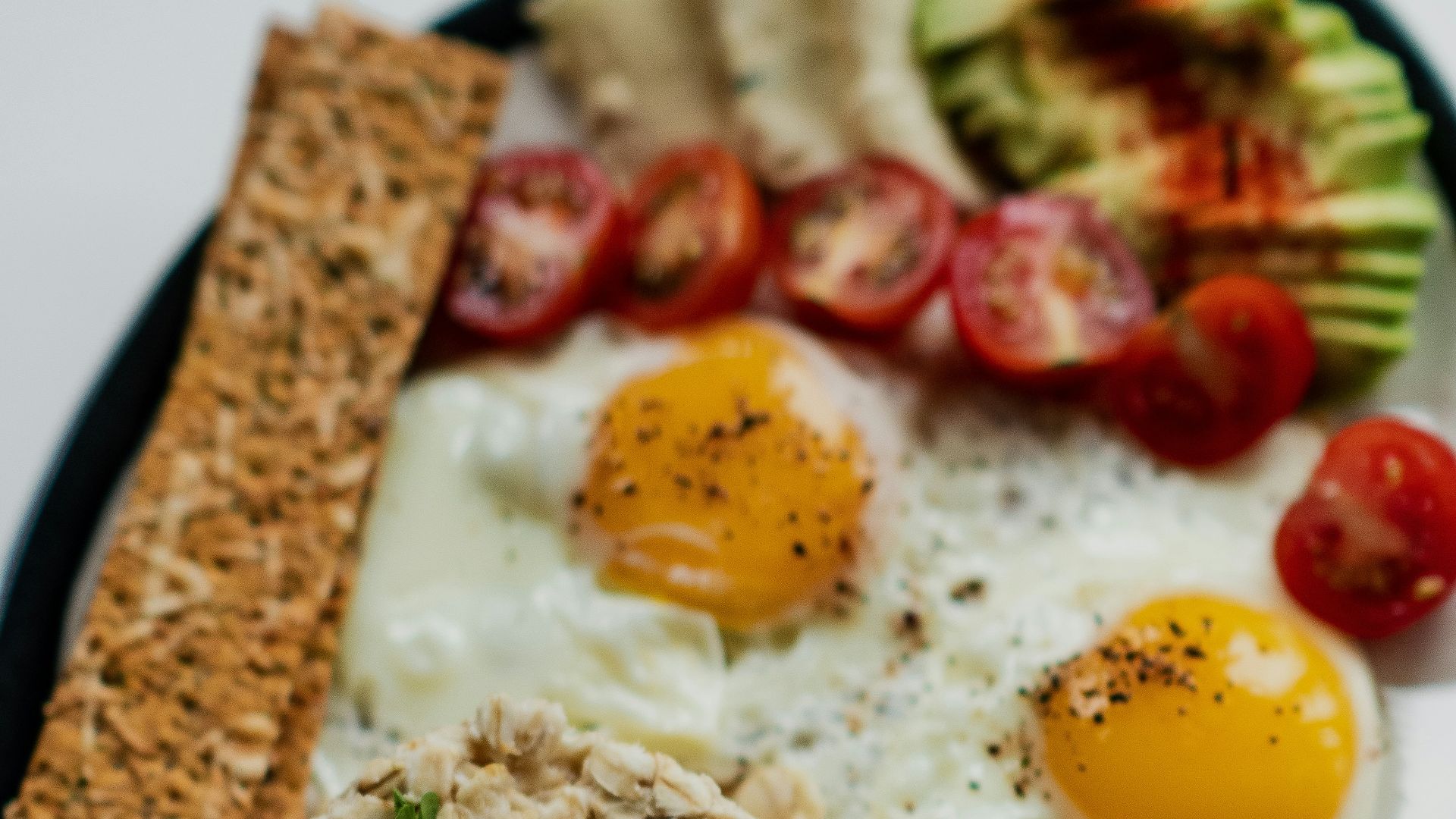 egg with sliced tomato and green vegetable on white ceramic plate
