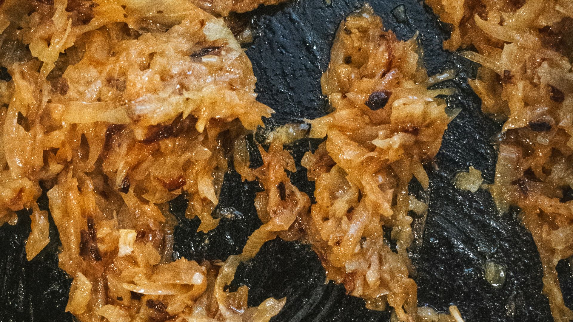 a frying pan filled with fried food and a wooden spoon