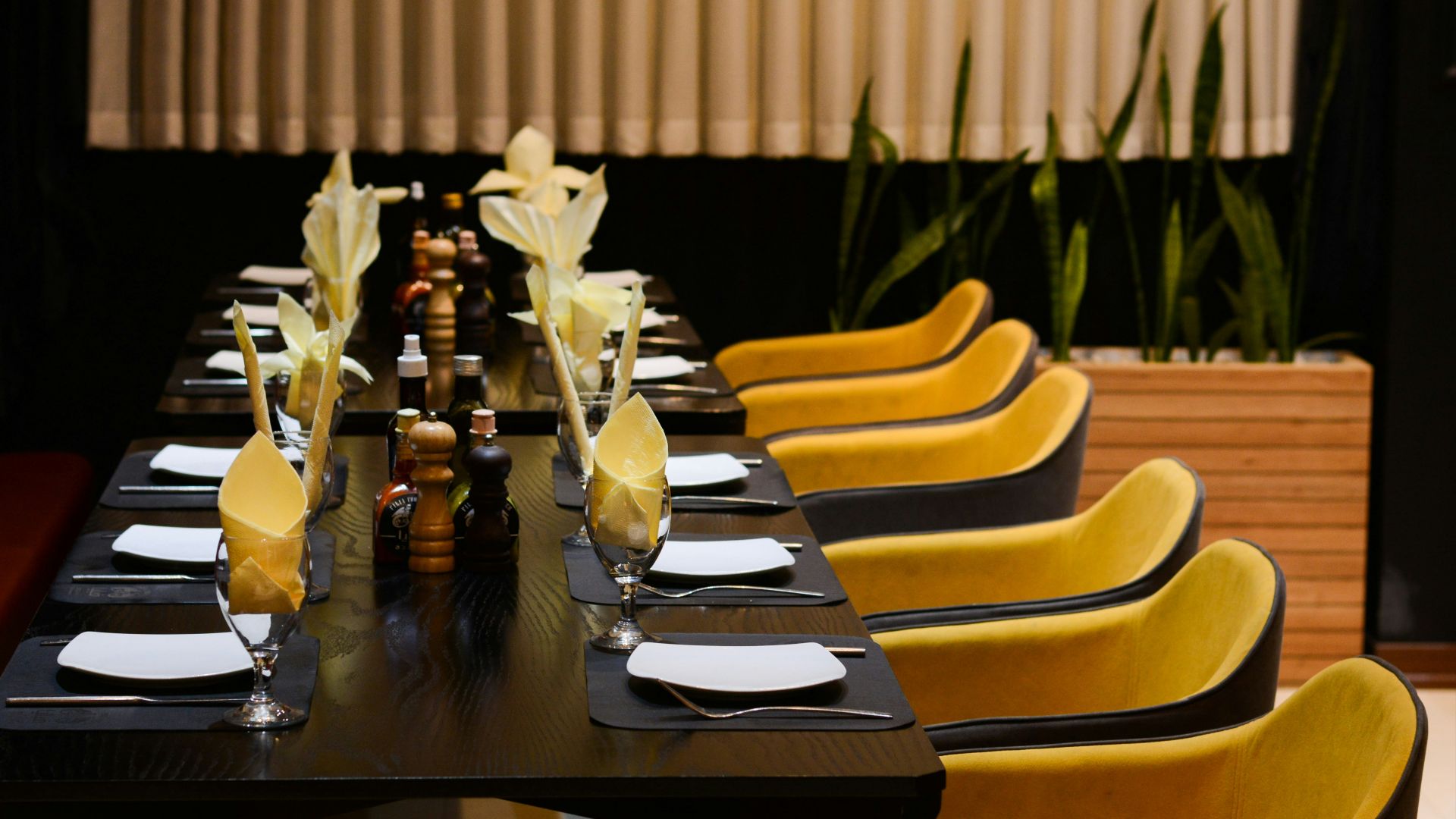 a long table with yellow chairs and black table cloths