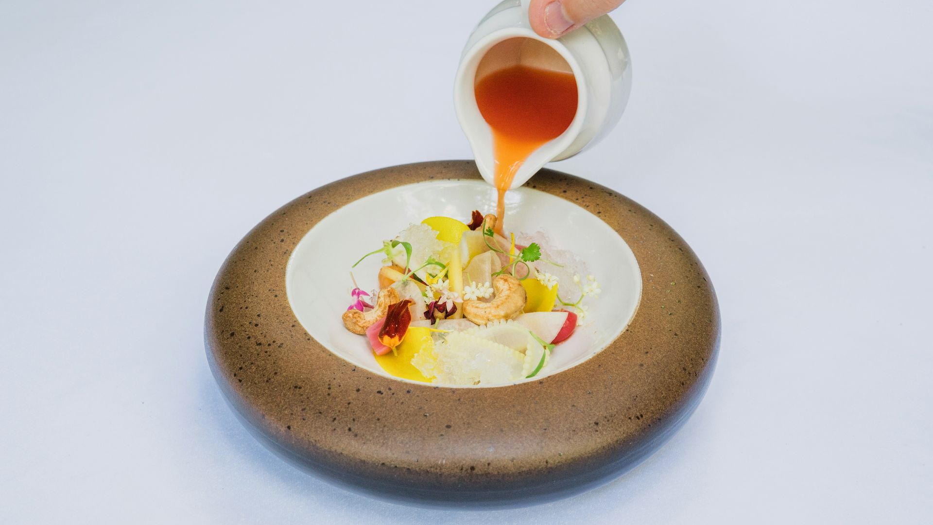 person holding white ceramic bowl with soup