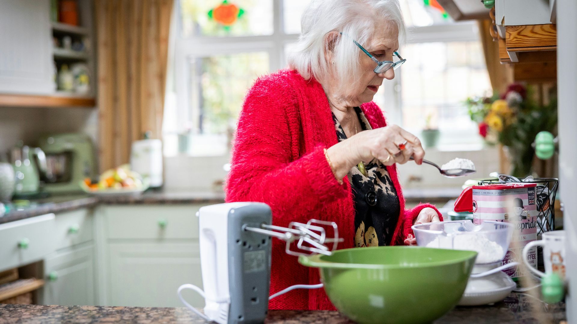 a woman in a red jacket is preparing food in a kitchen