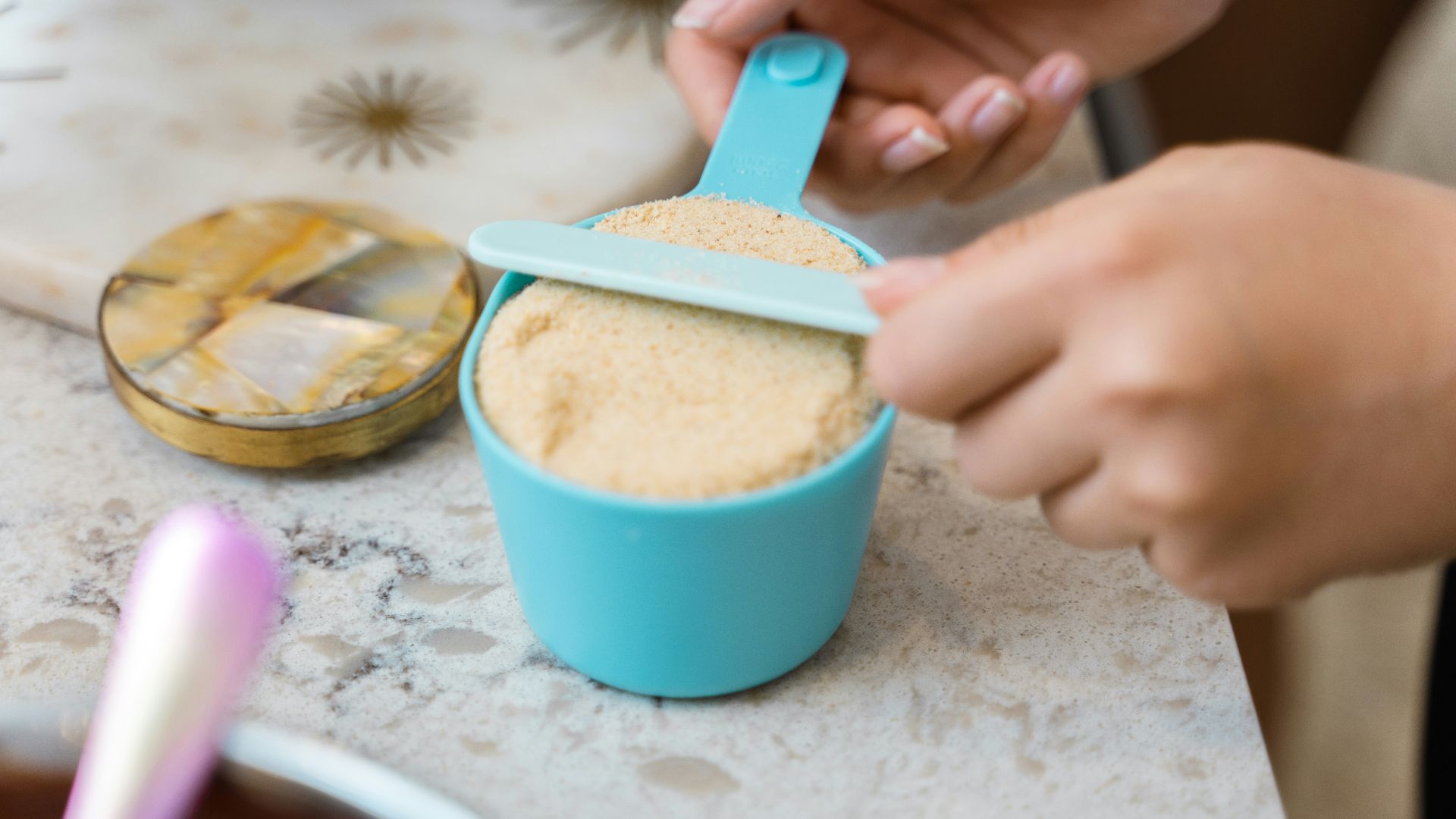 a person scooping sugar into a blue cup