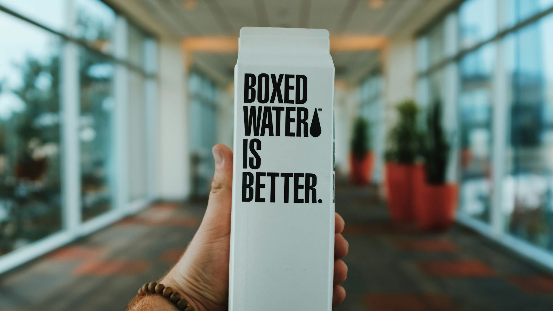 person holding boxed water is better box