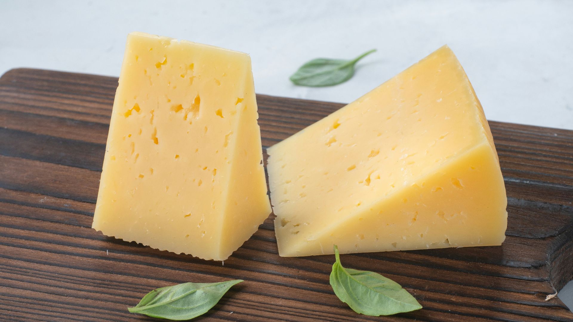 a couple of pieces of cheese sitting on top of a wooden cutting board
