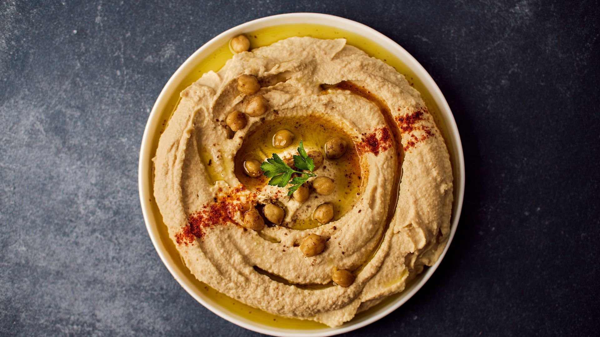 a bowl of hummus with a garnish on top