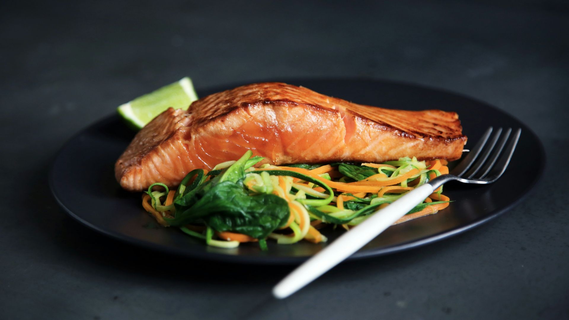 grilled fish, cooked vegetables, and fork on plate