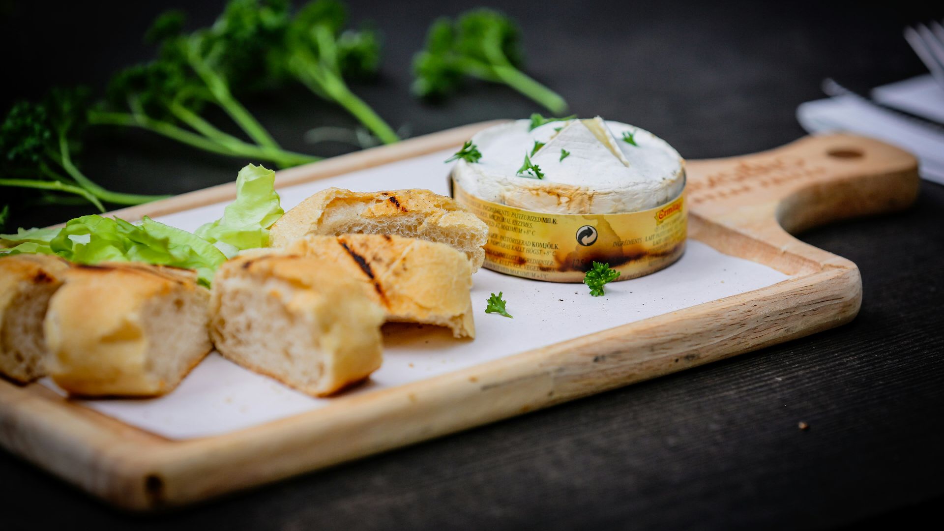a wooden cutting board topped with bread and vegetables