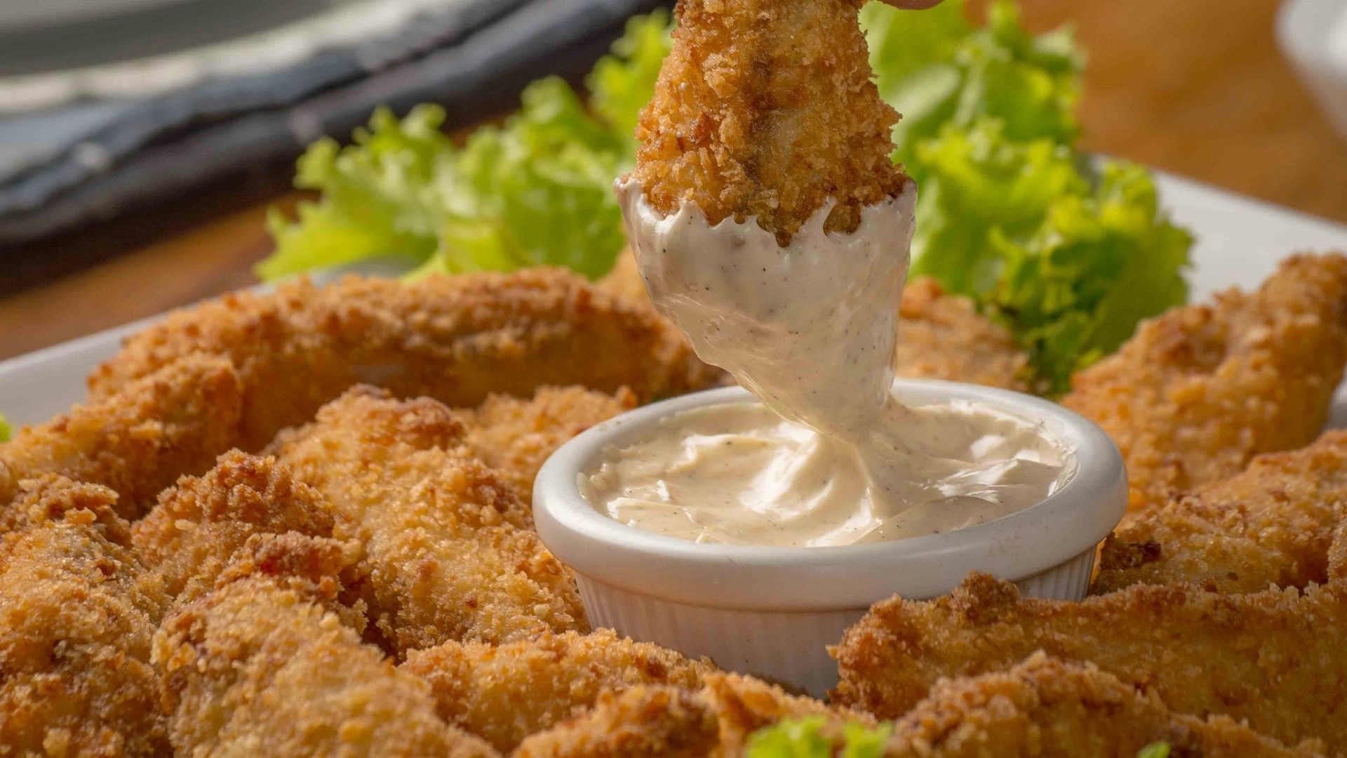 person dipping fried cuisine on dip
