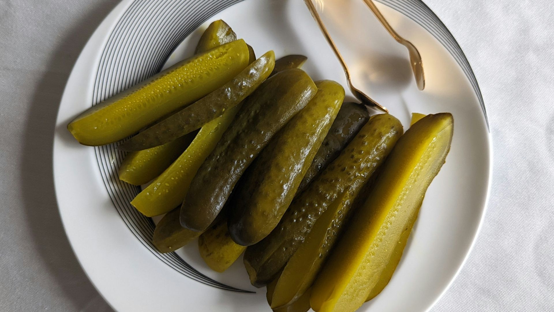 a white plate topped with pickles next to a fork