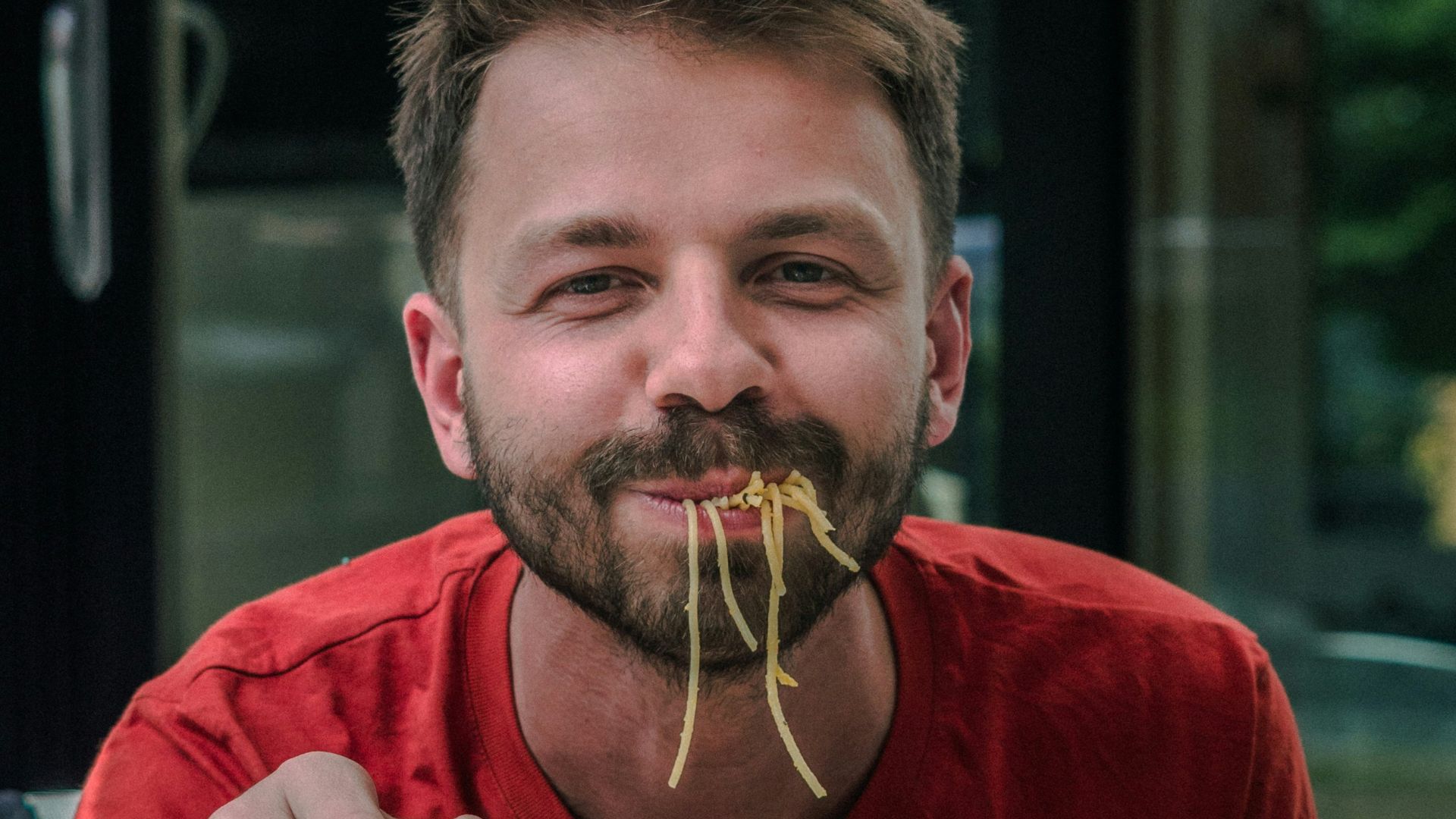 man in red crew neck t-shirt holding white and red labeled can