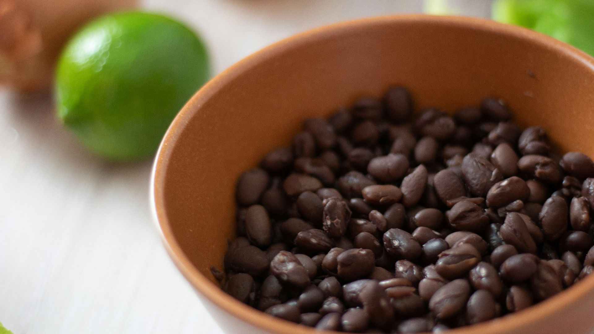 a bowl filled with black beans next to limes
