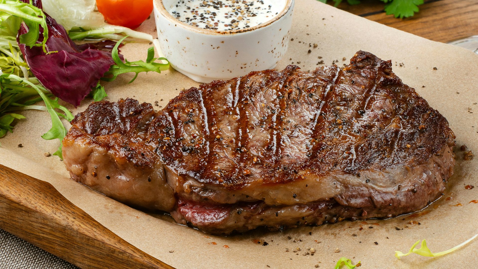 a steak with a side of salad and a glass of wine