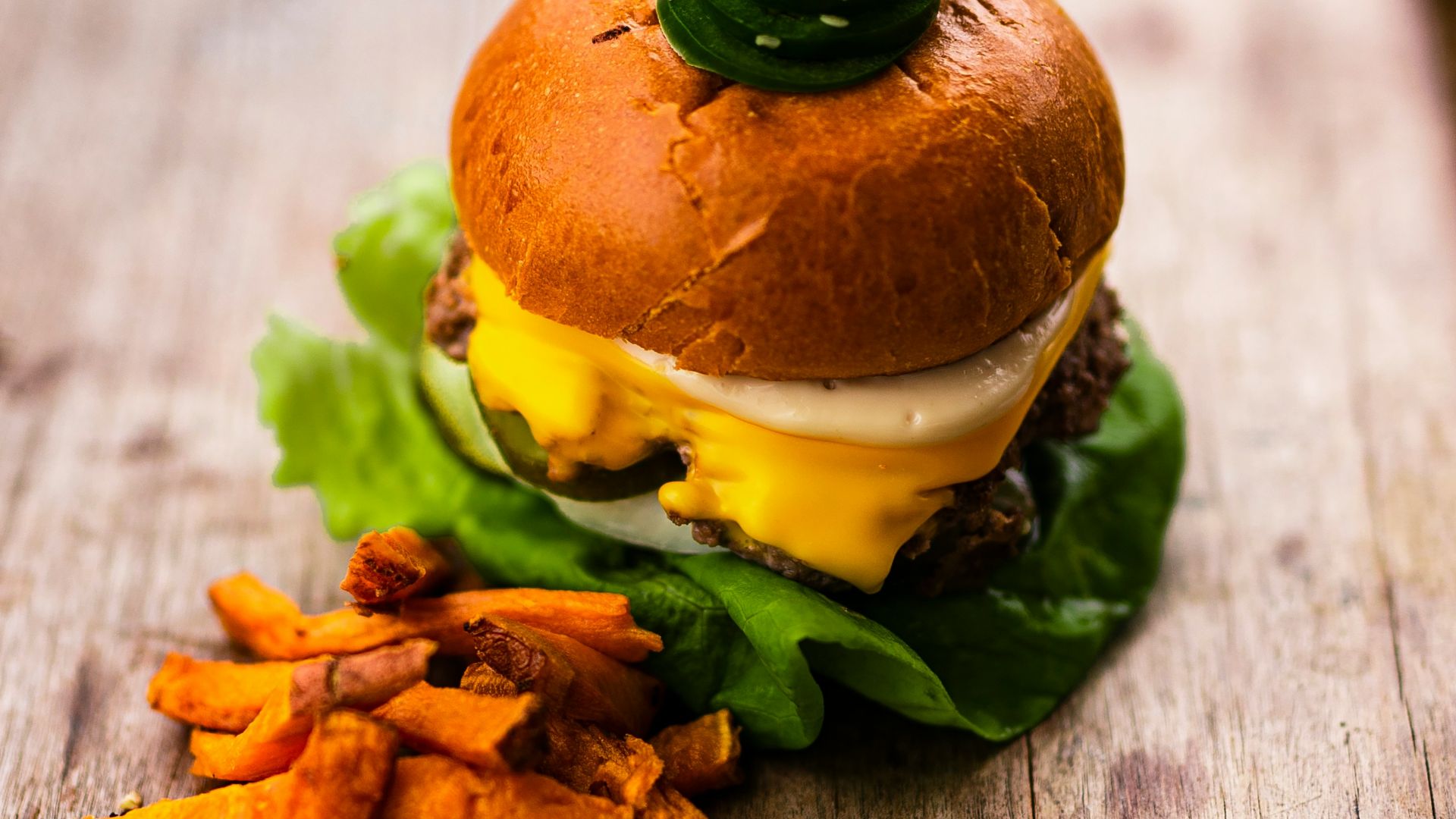 burger with lettuce and fries on brown wooden table