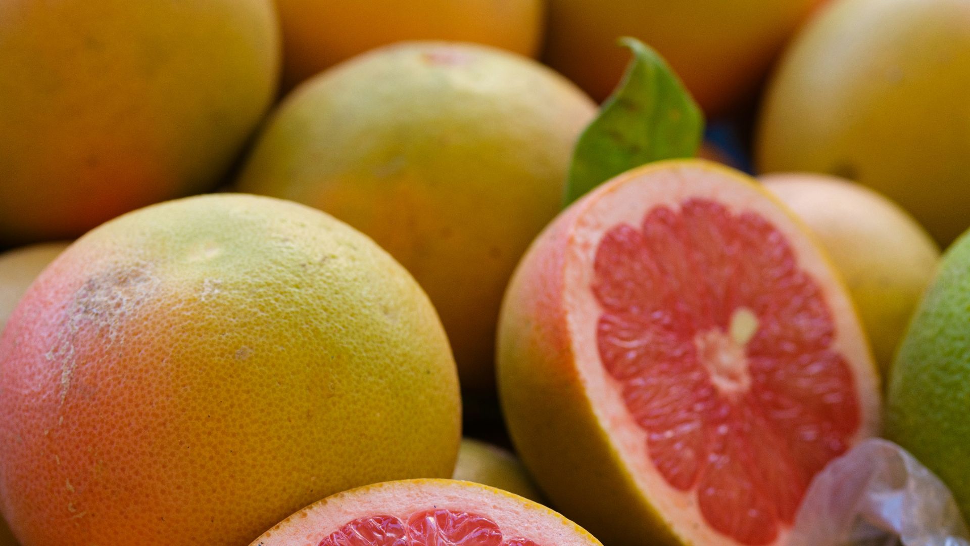 a pile of grapefruits with one cut in half