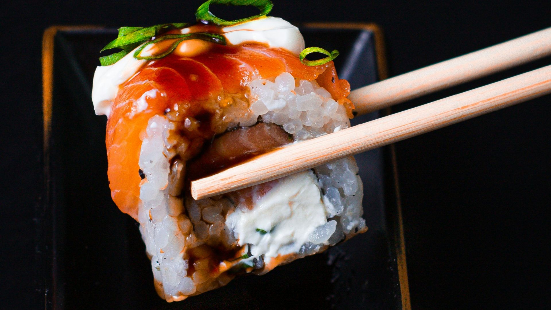 a black plate topped with sushi and chopsticks
