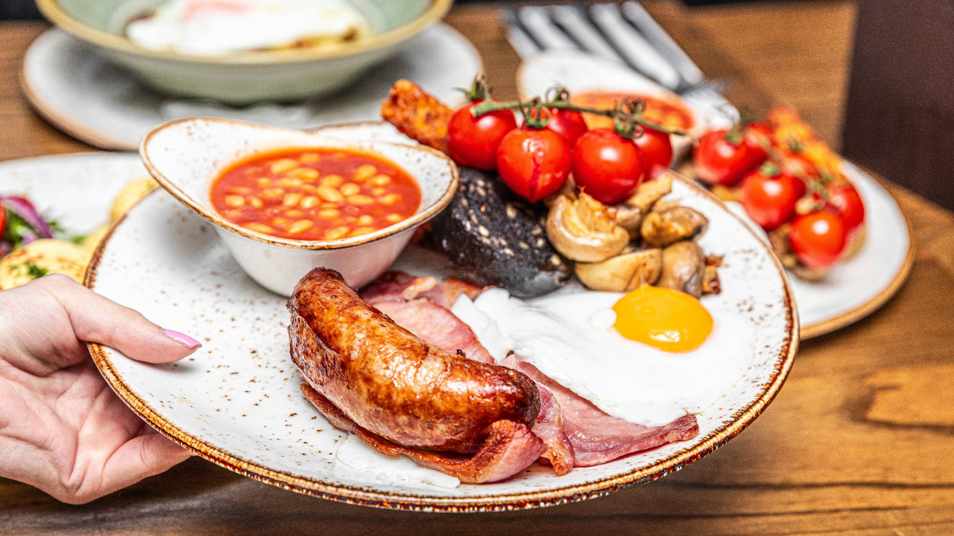 a person holding a plate of food on a table