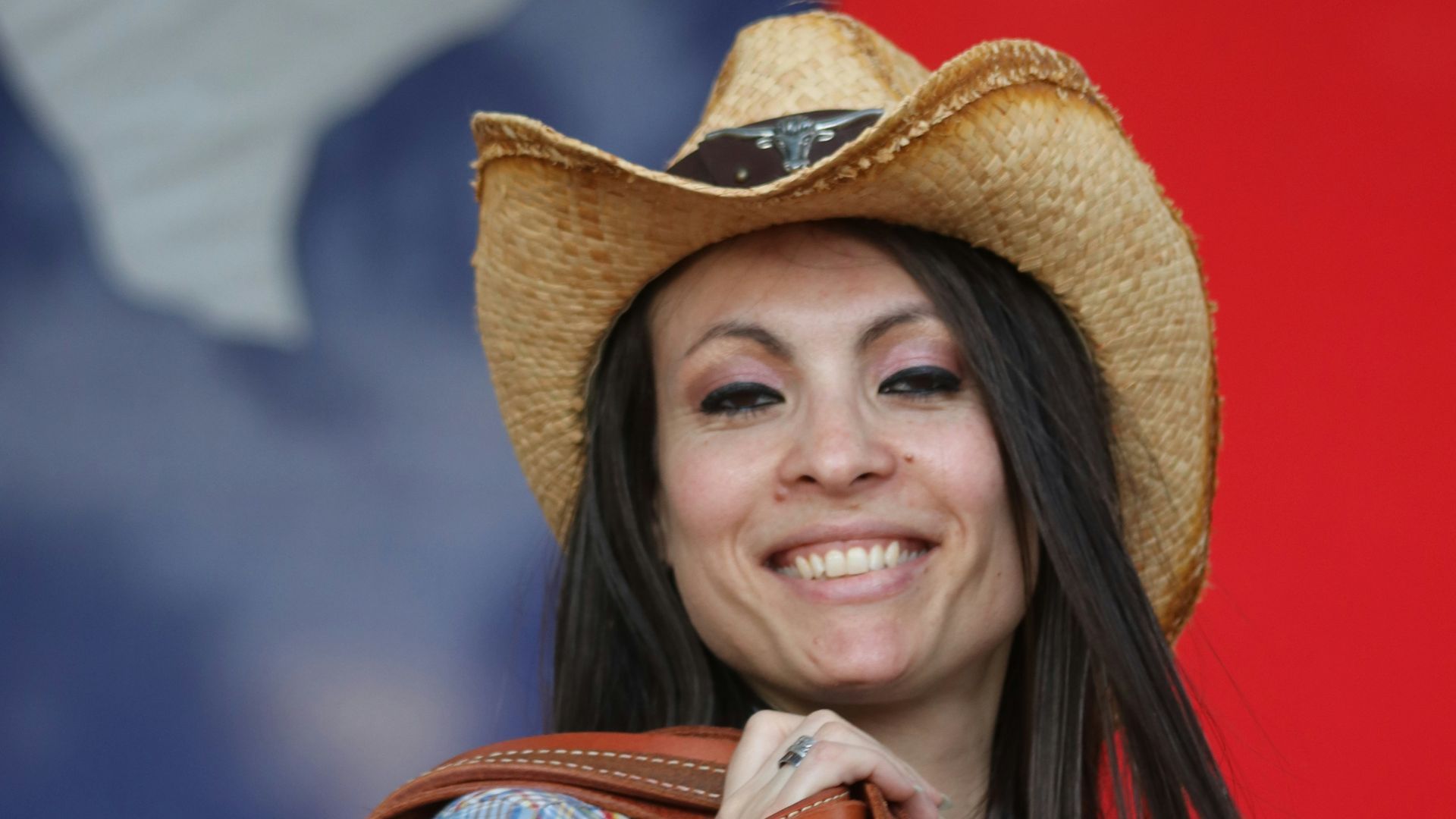 a woman wearing a cowboy hat and holding a brown bag