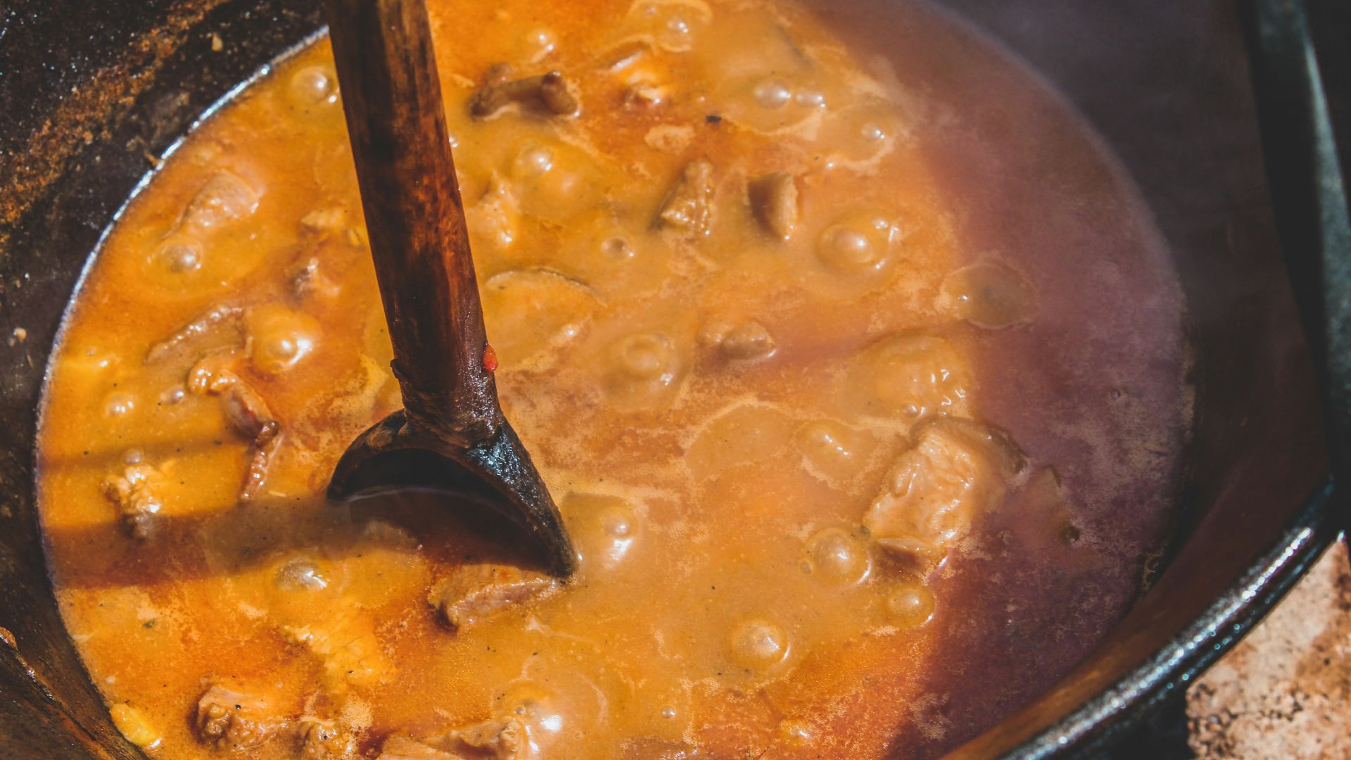 a pot of stew with a wooden spoon in it