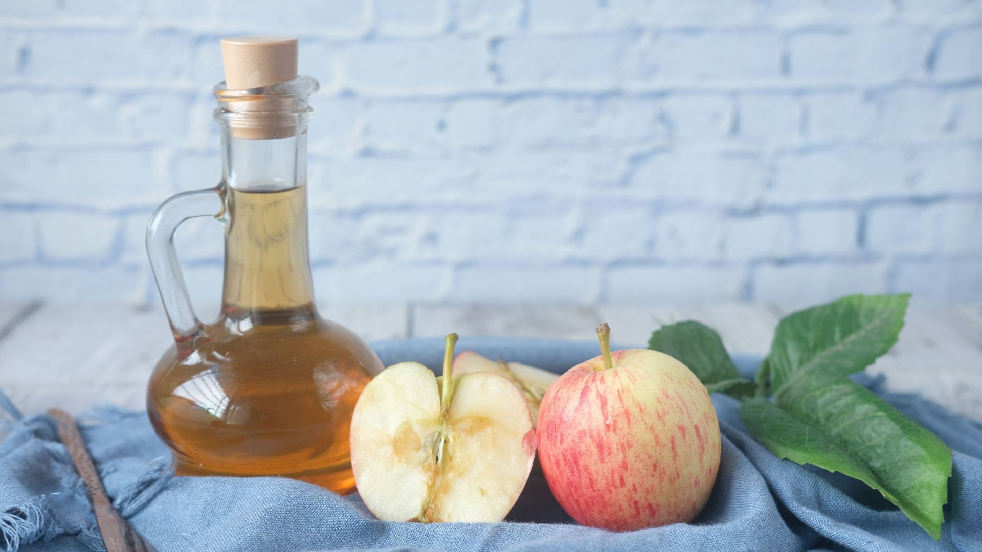clear glass bottle with red liquid beside sliced lemon on blue textile