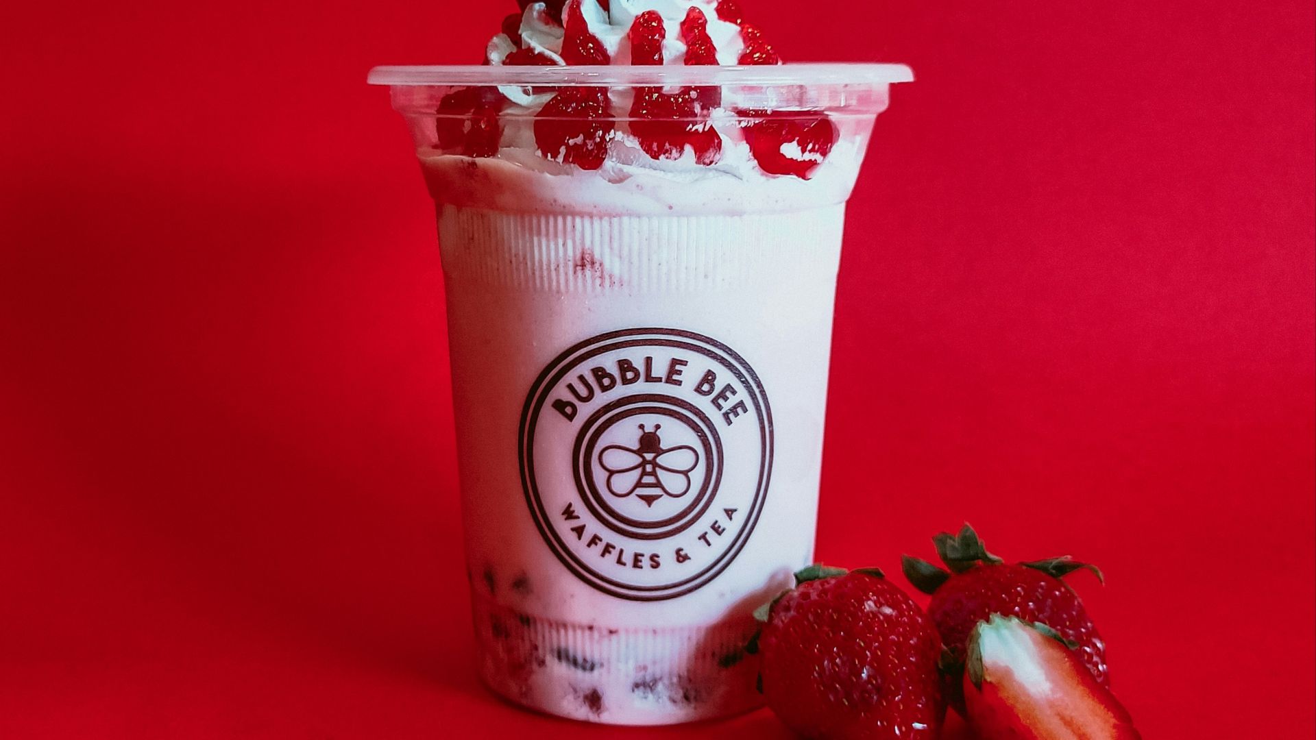 a cup of ice cream with strawberries on a red background