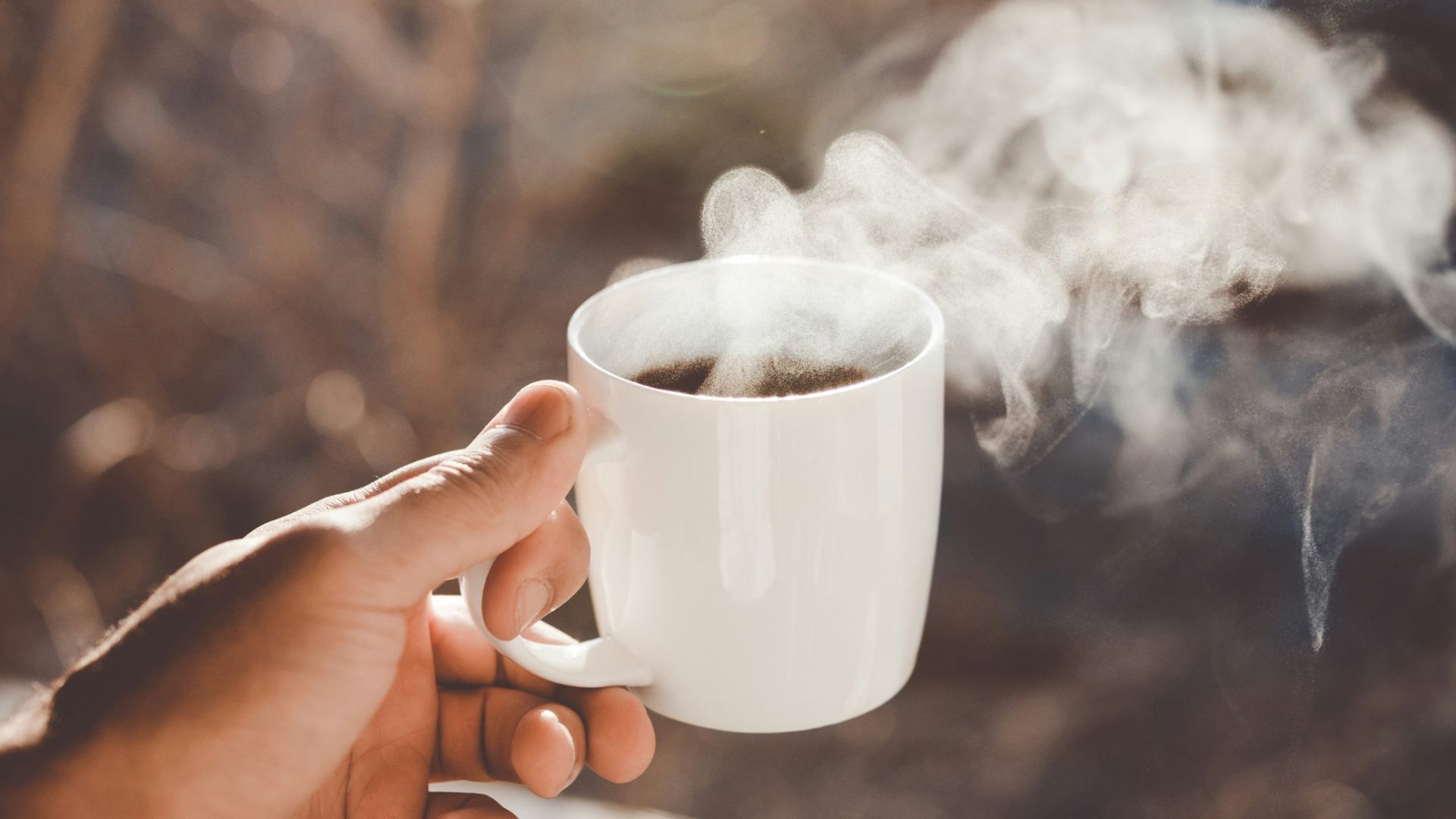 person holding white ceramic cup with hot coffee
