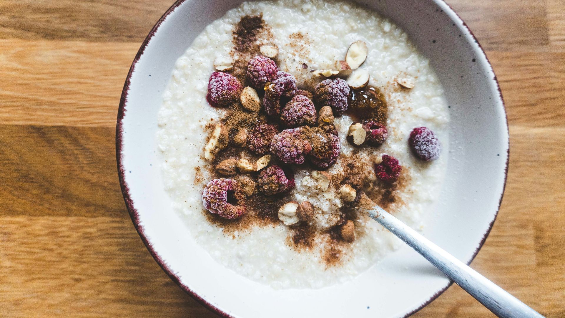 a bowl of oatmeal topped with raspberries and nuts