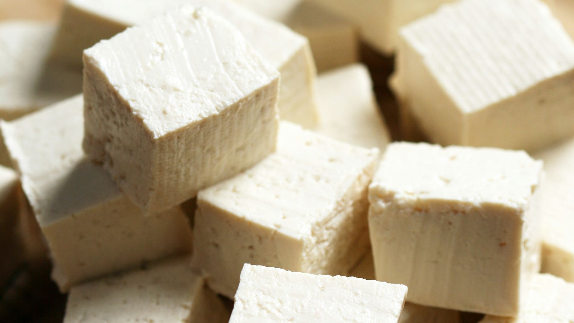 A pile of tofu cubes sitting on top of a cutting board