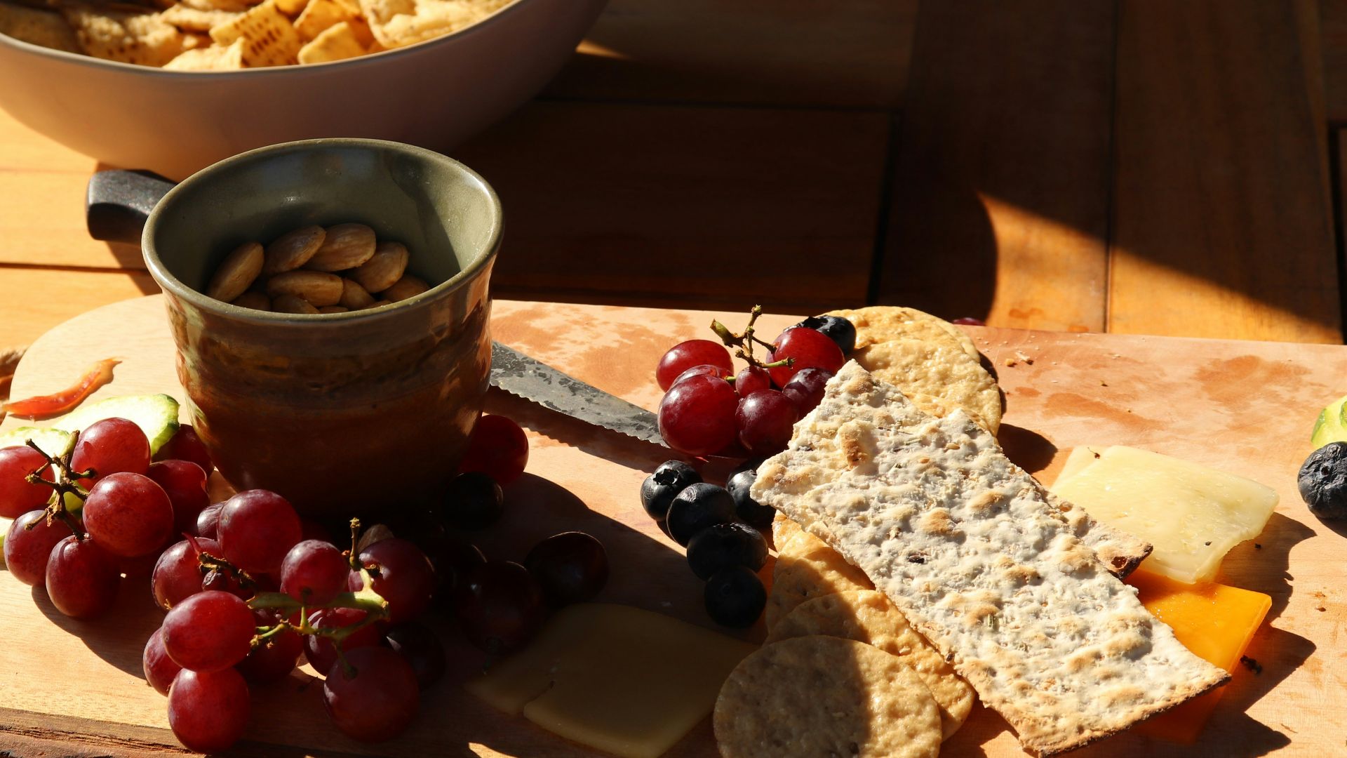a wooden cutting board topped with grapes and crackers