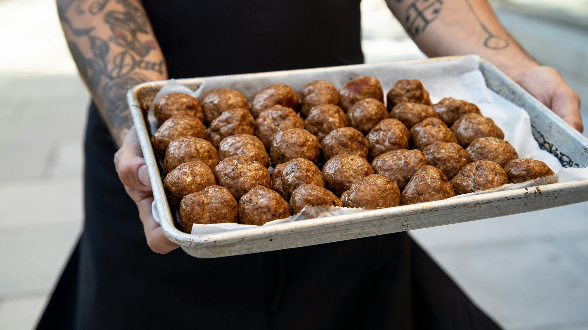 a person holding a tray of doughnuts on a sidewalk