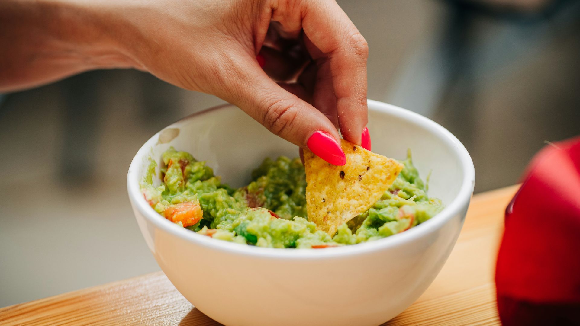 a person dipping a tortilla into a bowl of guacamole