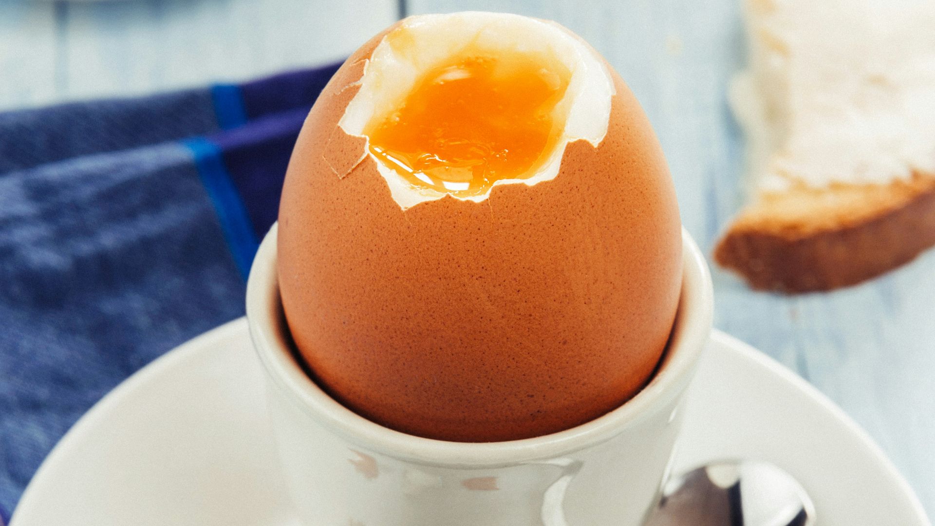 a cracked egg in a white bowl on a white plate