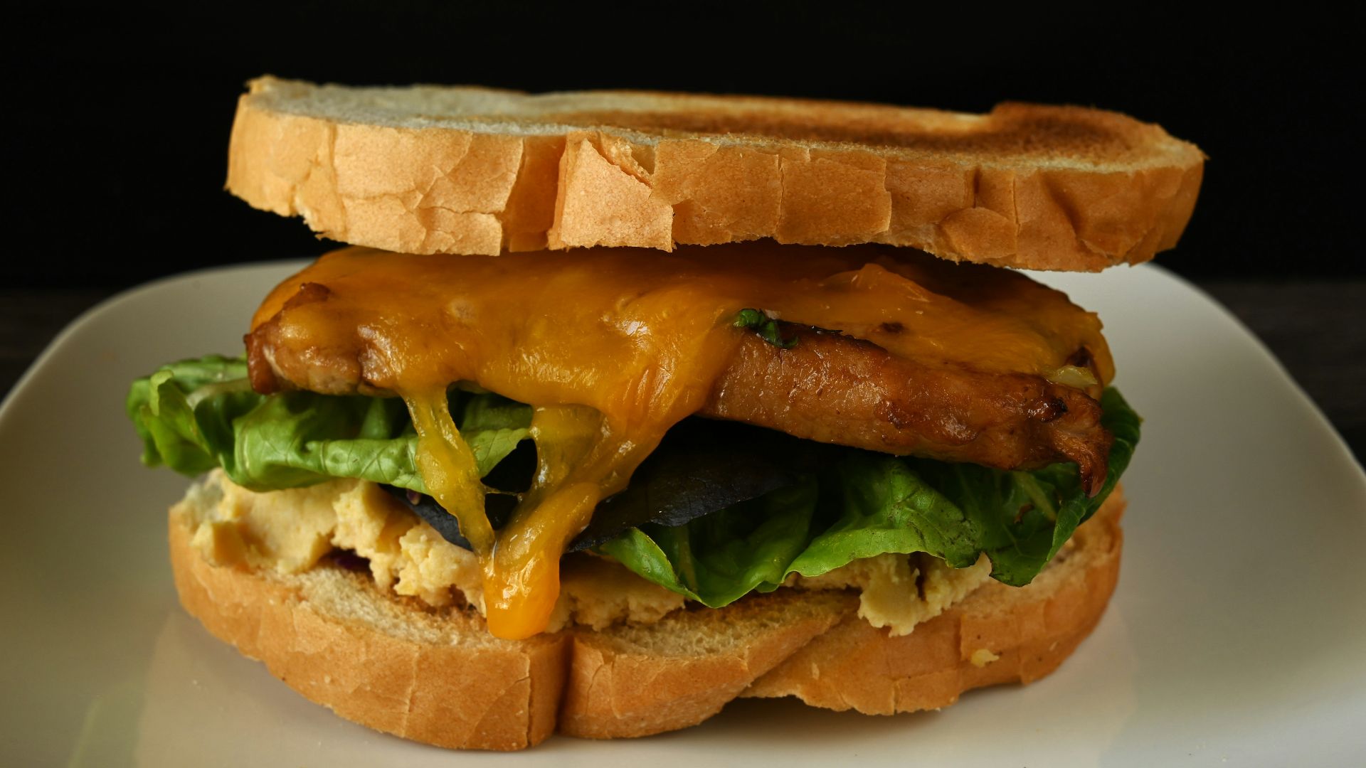 A sandwich on a plate with cheese and lettuce