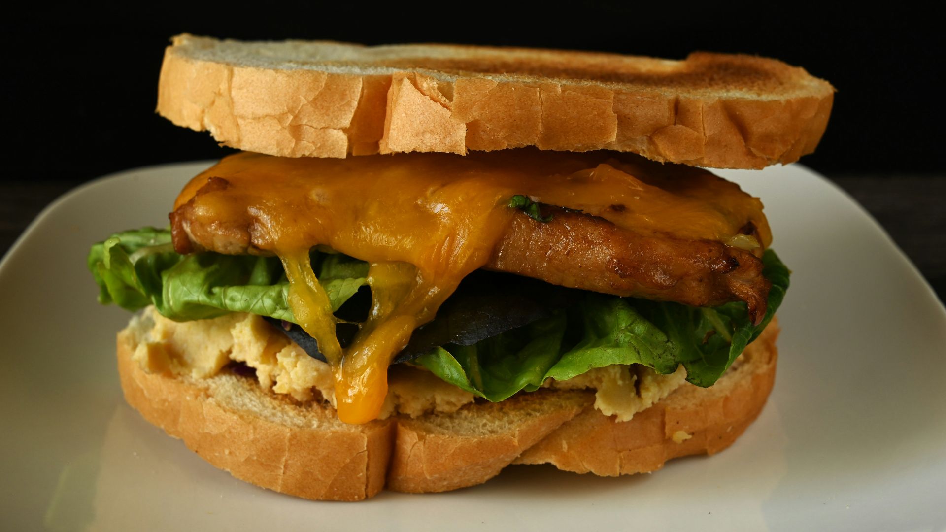 A sandwich on a plate with cheese and lettuce