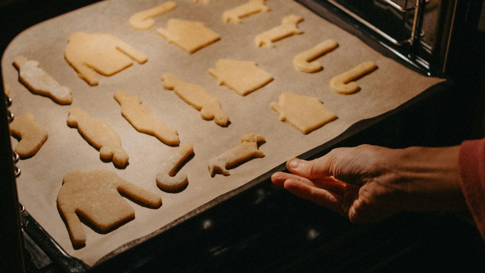 Hand placing cookie sheet into oven