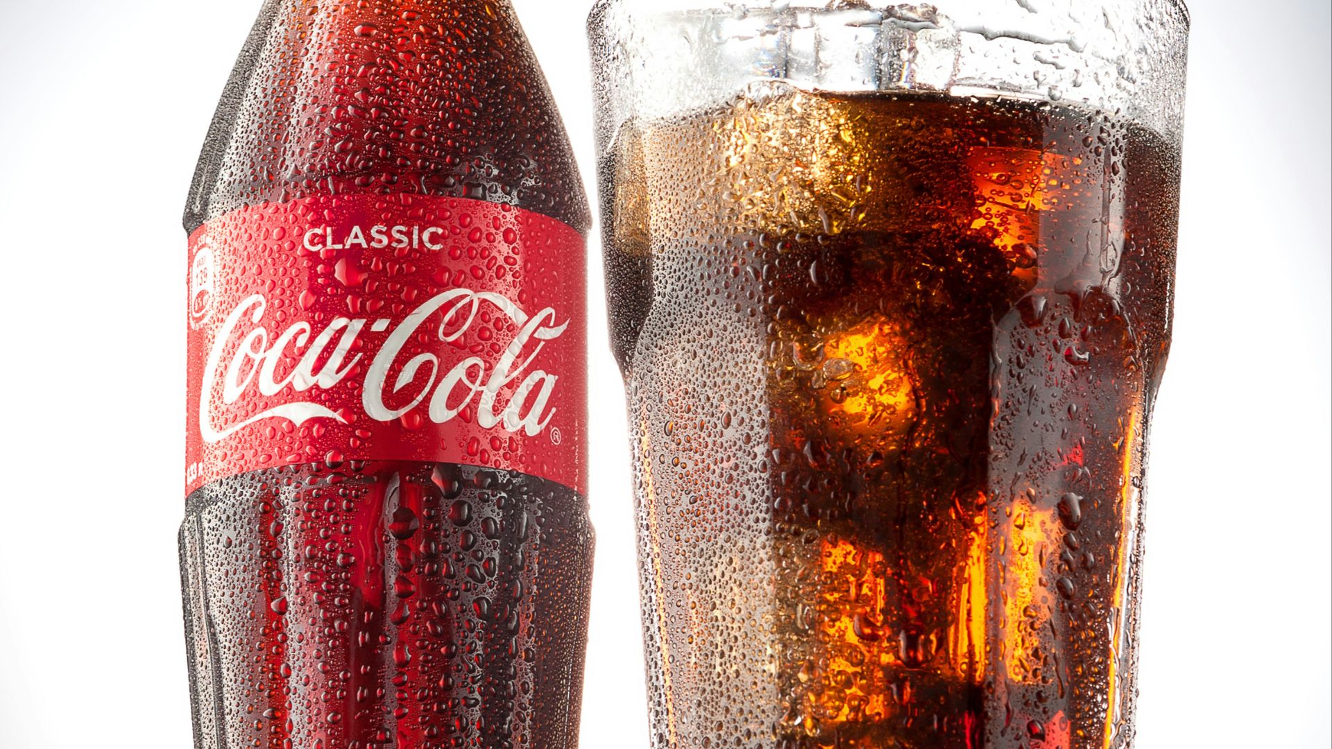 coca cola bottle beside drinking glass