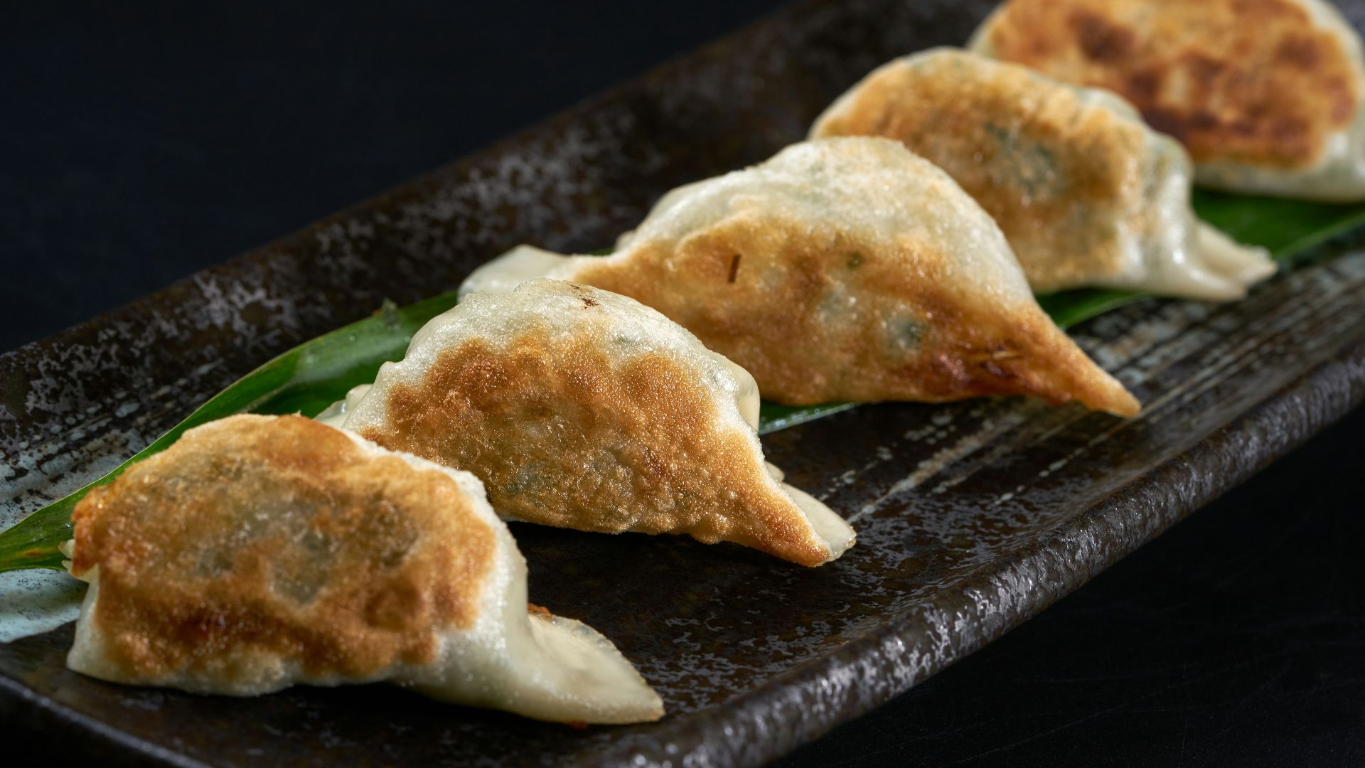 a black plate topped with three dumplings of food