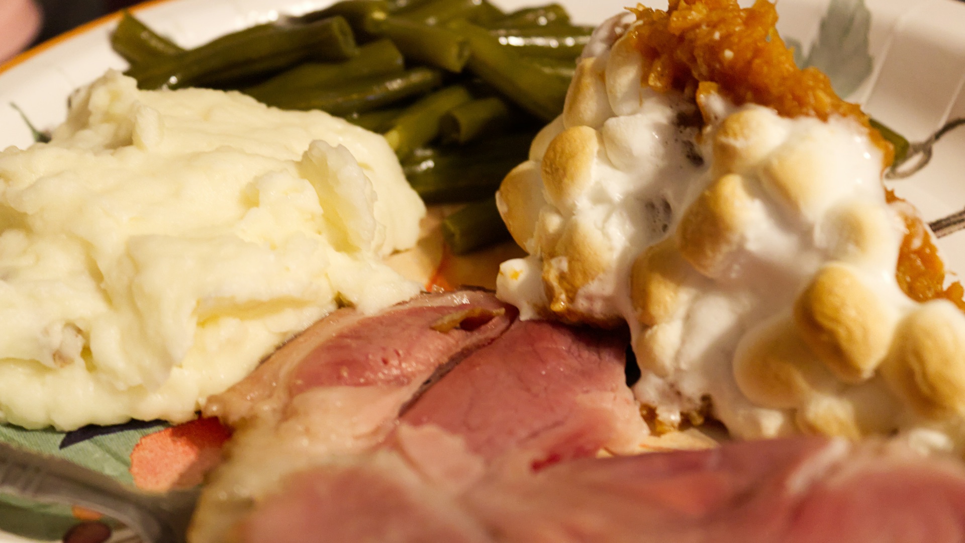 A white plate topped with meat, mashed potatoes and green beans