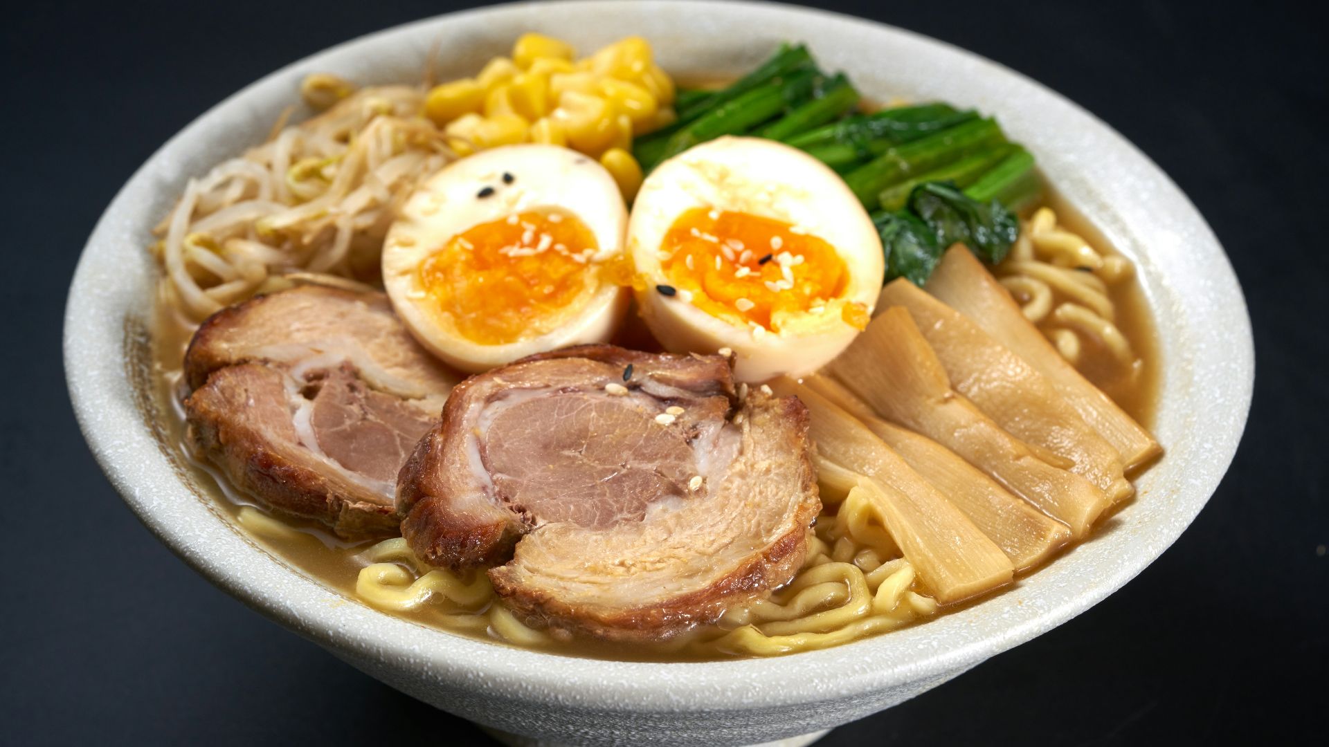 a bowl of ramen with meat, eggs, noodles and vegetables