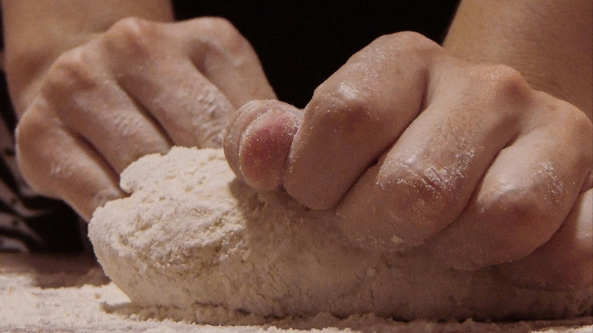 person holding white powder on brown wooden table