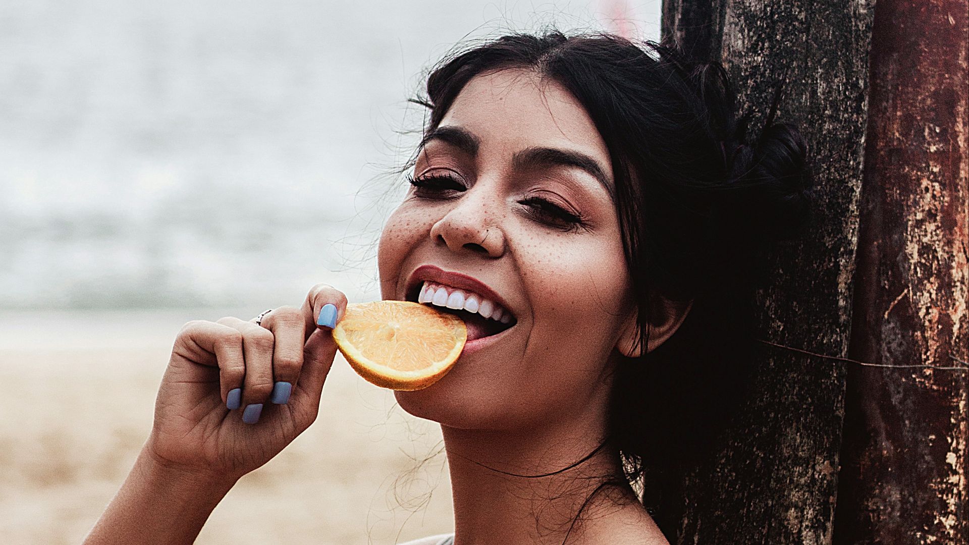 a woman sitting on the beach brushing her teeth