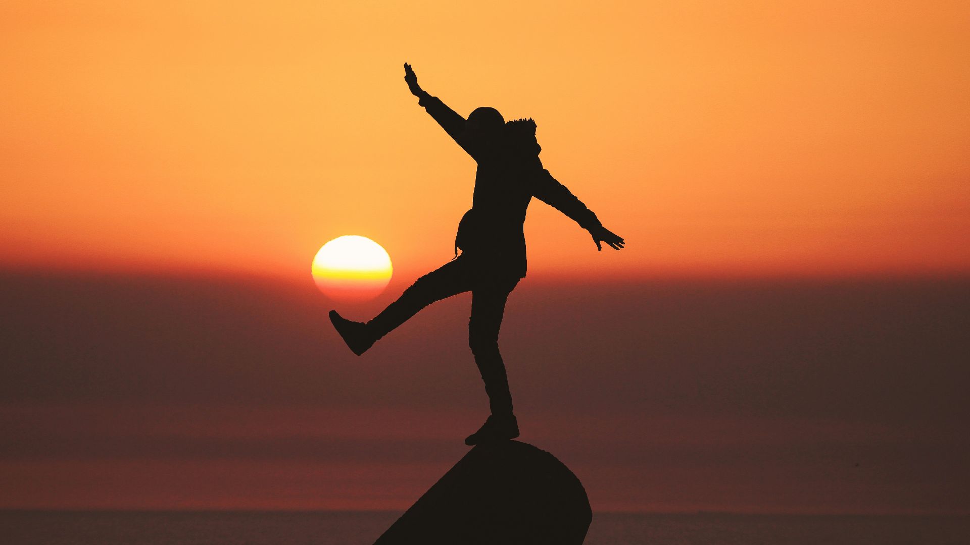 photo of silhouette photo of man standing on rock