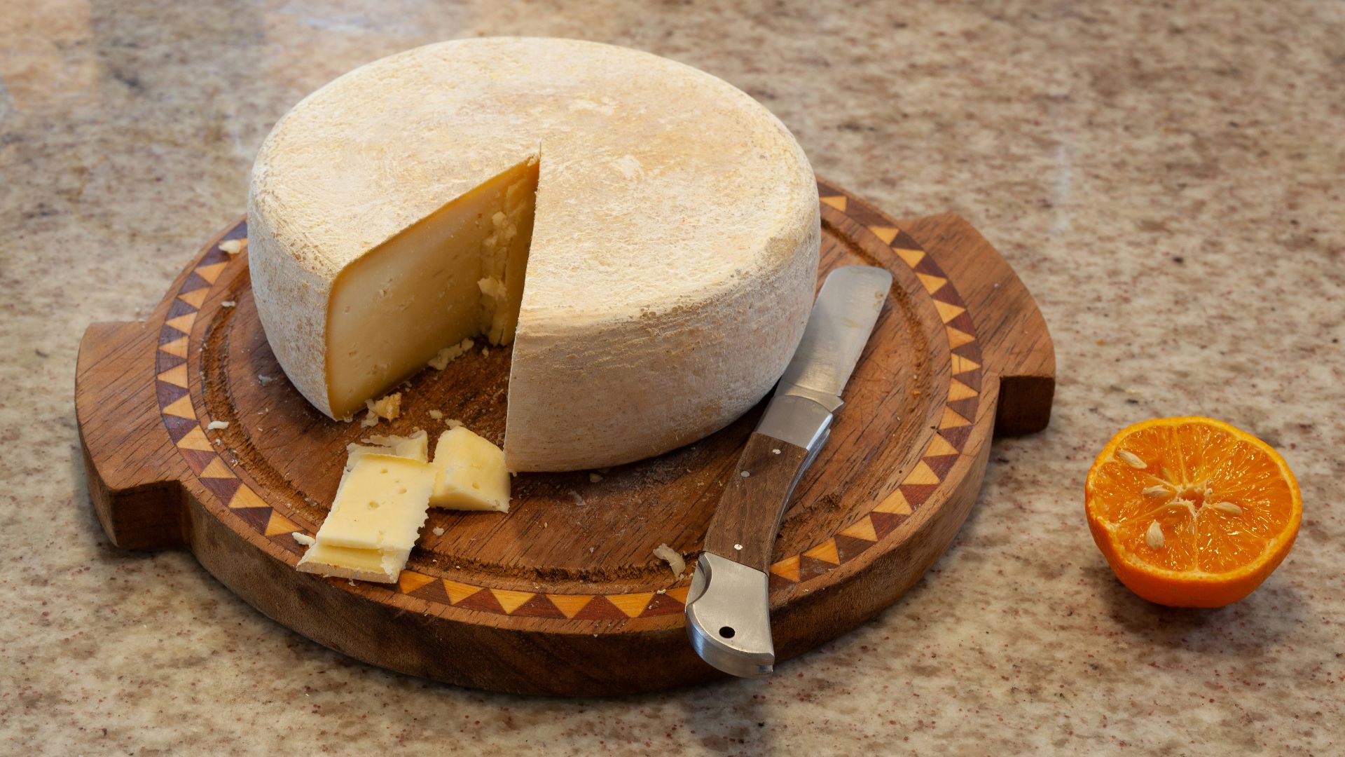 a cheese board with a piece of cheese on top of it