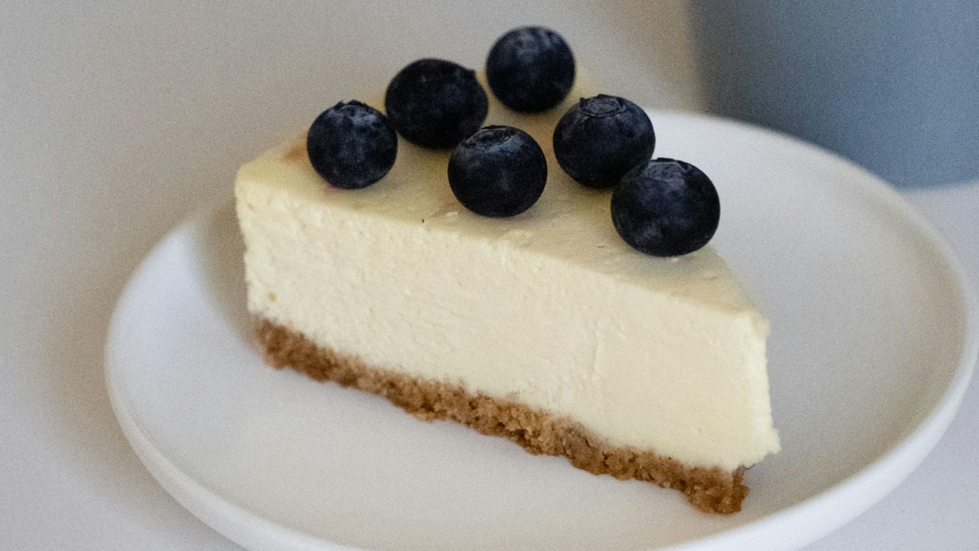 a piece of cheesecake on a plate next to a cup of coffee